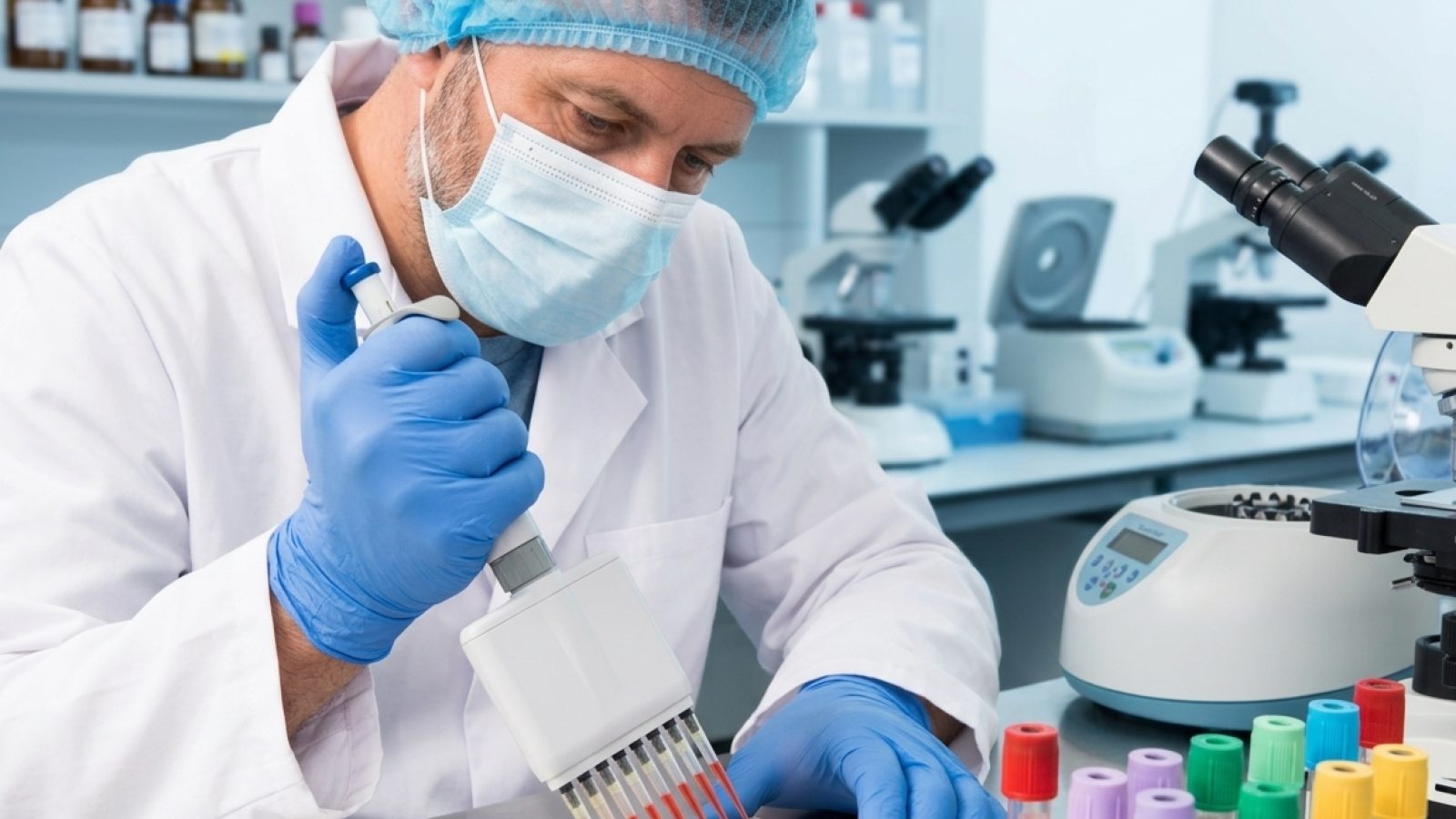 Profissional de laboratório pipetando amostras ao lado de tubos de coleta de sangue